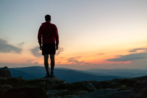 istock Man celebrating sunset looking at view in mountains 1055528598