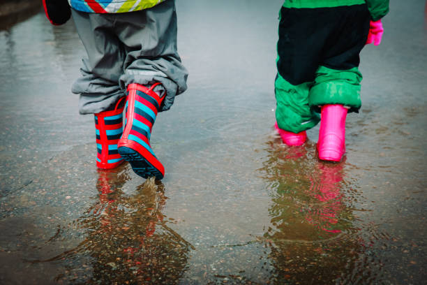 istock kids in rubber boots playing in water puddle 1055533182