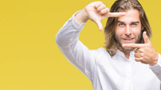 istock Young handsome man with long hair over isolated background smiling making frame with hands and fingers with happy face. Creativity and photography concept. 1055535476