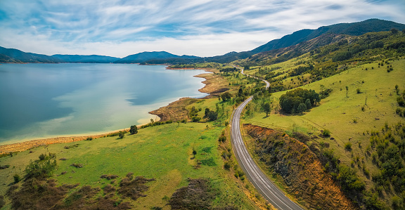 Road winding through lake shore and mountains. Scenic aerial panorama of Australia