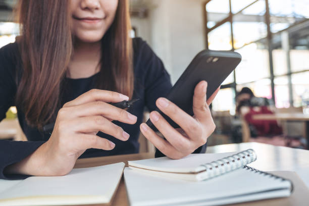 istock Closeup image of an Asian woman holding , using and looking at smart phone while working 1055546044