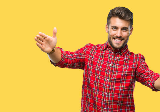 istock Young handsome man over isolated background looking at the camera smiling with open arms for hug. Cheerful expression embracing happiness. 1055547448