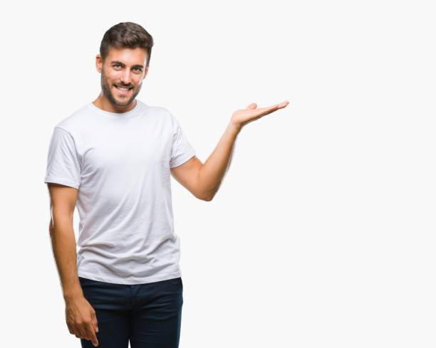 istock Young handsome man over isolated background smiling cheerful presenting and pointing with palm of hand looking at the camera. 1055547600
