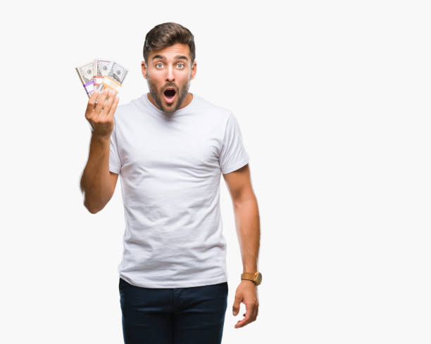 istock Young handsome man holding stack of dollars over isolated background scared in shock with a surprise face, afraid and excited with fear expression 1055547970