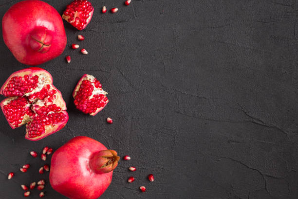 istock Ripe red pomegranate closeup photography on black background with copy space. 1055553328