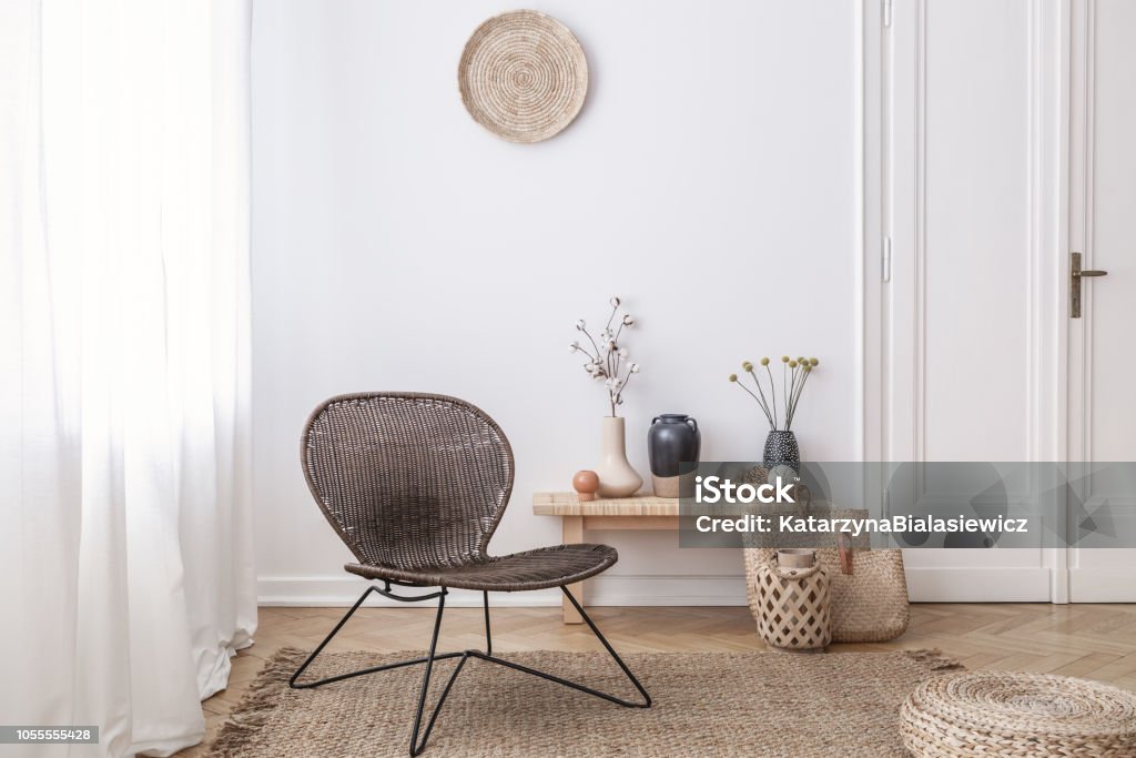 Dunkle, moderne Korbstuhl in einem weißen Wohnzimmer Interieur mit einer Holzbank und Dekorationen aus Naturmaterialien gefertigt - Lizenzfrei Das Leben zu Hause Stock-Foto