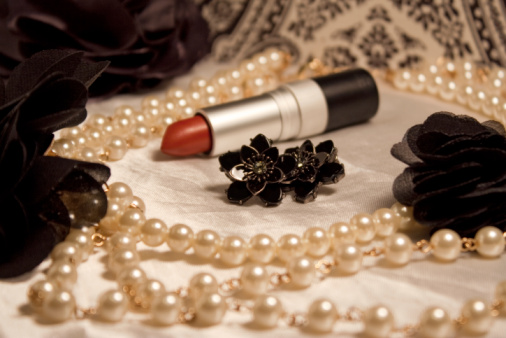 Tabletop photo of various beauty items, sepia toned with shallow depth of field focused on earrings to create a vintage-styled photo.