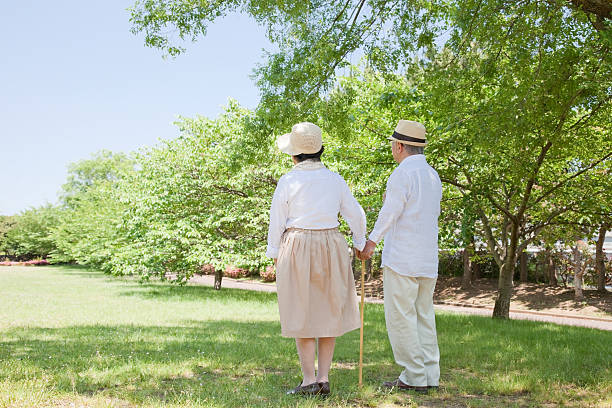 Rear view of Japanese couple walking in park stock photo