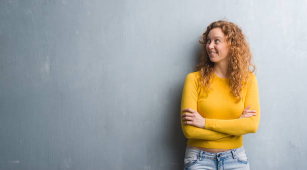 istock Young redhead woman over grey grunge wall smiling looking side and staring away thinking. 1055568254