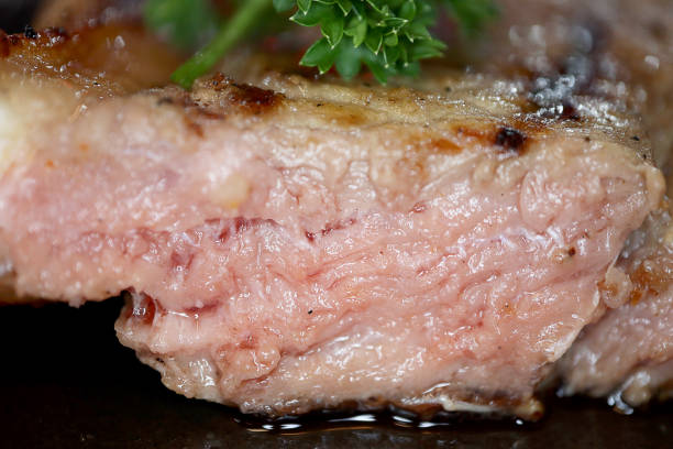 Close-up low angle photo of Premium quality T-Bone Beef Medium Rare Steak with black pepper in black plate background, Foods concept.