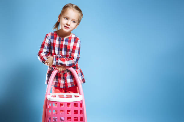 istock Little girl with toy suitcase on blue background. 1055577032