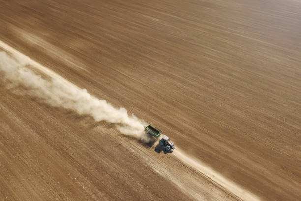 istock Tractor going trough agriculture field Aerial view 1055579354