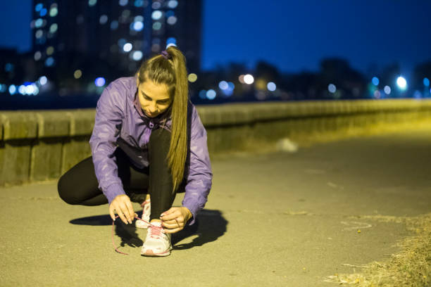 istock Woman tying her shoelaces at night 1055587240