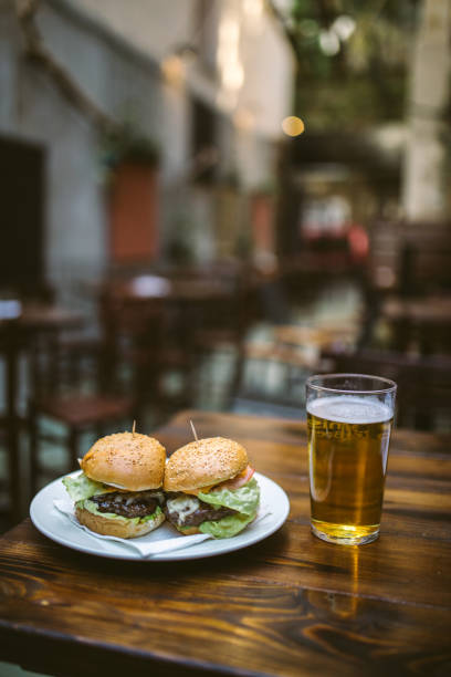 Delicious Burgers Served With Fresh Cold Glass Of Beer At Sunbathed Restaurant Garden
