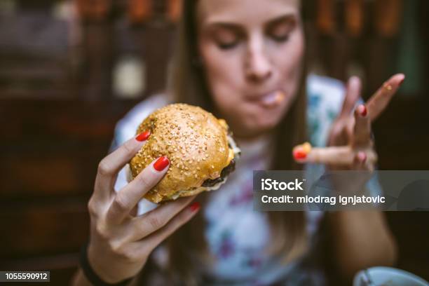 Mujer Disfrutando De La Deliciosa Hamburguesa Foto de stock y más banco de imágenes de Comer - Comer, Hamburguesa - Alimento, Alimento