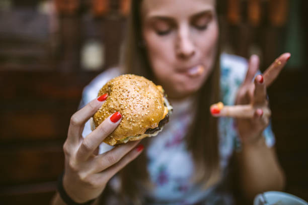 Woman Enjoying Delicious Burger Gourmand Girl Eating Tasty Hamburger at Fast Food Restaurant mouth full stock pictures, royalty-free photos & images