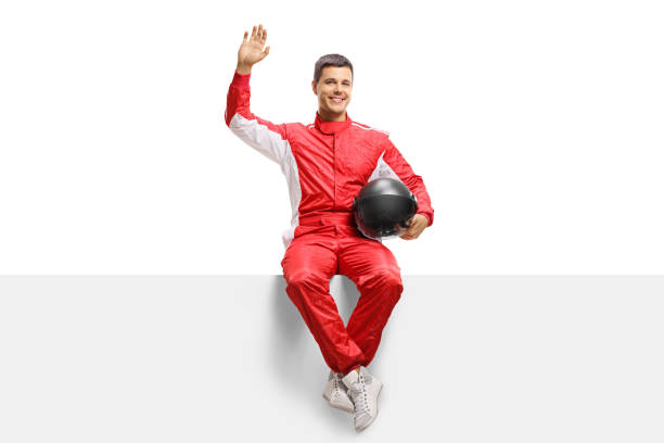 istock Race driver sitting on a panel and waving at the camera 1055597104