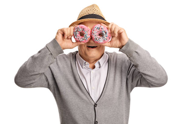 istock Mature man holding donuts in front of his eyes 1055597204