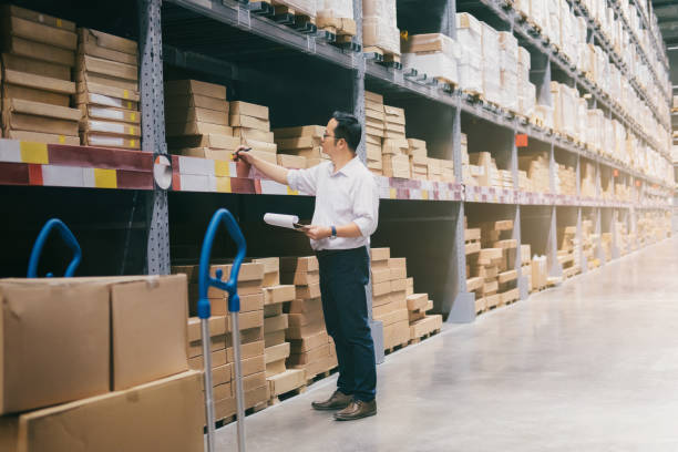 Man warehouse worker checking goods at warehouse. Wholesale, logistic, business, export and people concept - Man warehouse worker checking goods at warehouse. portage valley stock pictures, royalty-free photos & images