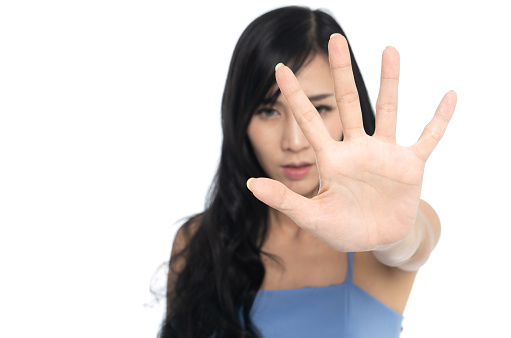 Woman showing her hand sign cover her face to say no on white background