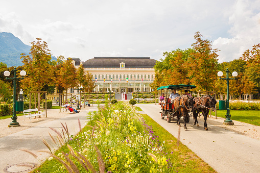 Bad Ischl, Austria - September 2, 2016: A horse-drawn carriage with tourists rides through a park in front of the Congress and Theaterhouse (Kongress & Theaterhaus) in Bad Ischl, Austria.