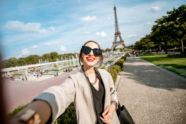 Lifestyle portrait of a young woman walking in front of the famous Eiffel tower during the sunny day in Paris