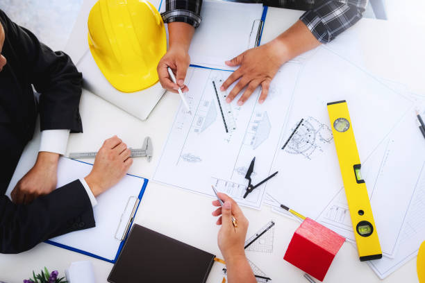 istock engineer people meeting working and pointing at a drawings in office for discussing. Engineering tools and construction concept. 1055603906