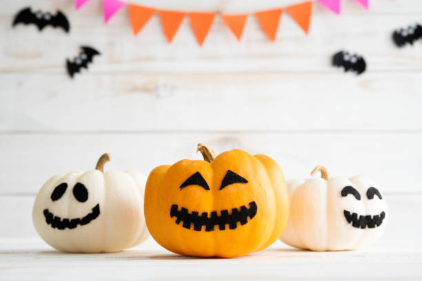 istock White and yellow ghost pumpkins with witch hat on white wooden borad background with bat. halloween concept. 1055608128