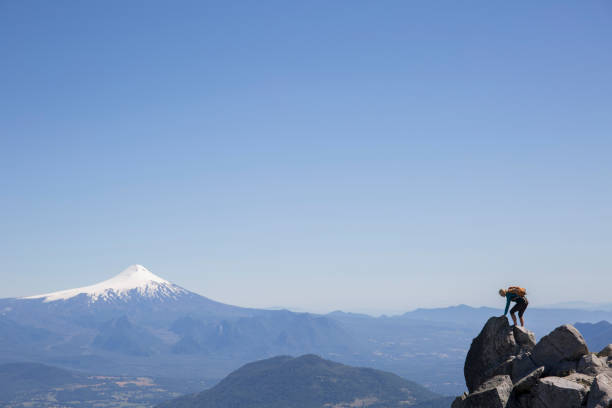 istock Female hiker climbs to ridge summit, above distant volcano 1055608334