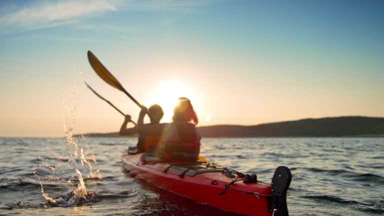 SLO MO Couple in a red sea kayak passing by on the water in sunshine