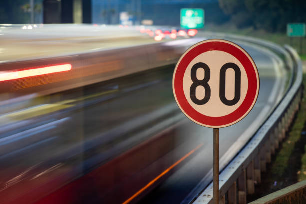 Long exposure shot of traffic sign showing 80 km/h speed limit on a highway full of cars in motion blur during the night Long exposure shot of traffic sign showing 80 km/h speed limit on a highway full of cars in motion blur during the night kilometer photos stock pictures, royalty-free photos & images