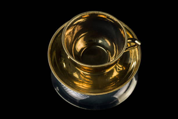 istock Gilded tea cup on a saucer isolated on a black background 1055612448