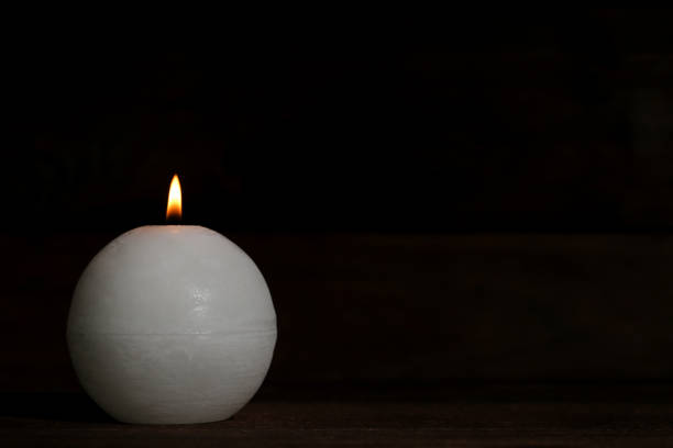 istock White burning candle on black background 1055614240