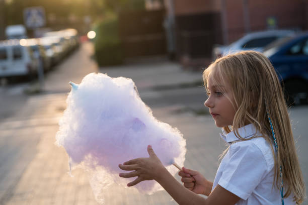 istock Pretty 7 years old blue eyes child eating sugar cotton 1055614664