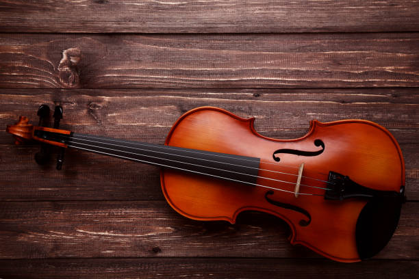 istock Violin on brown wooden table 1055615258