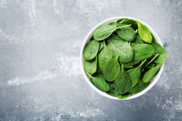 istock Spinach leafs in bowl on gray wooden table 1055617890