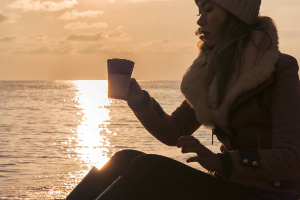 istock Drinking cup of coffee on sunset at the beach 1055617894