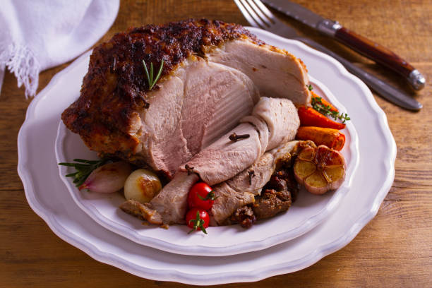 istock Baked ham with vegetables: carrots, onions, tomatoes, garlic and herbs 1055620044