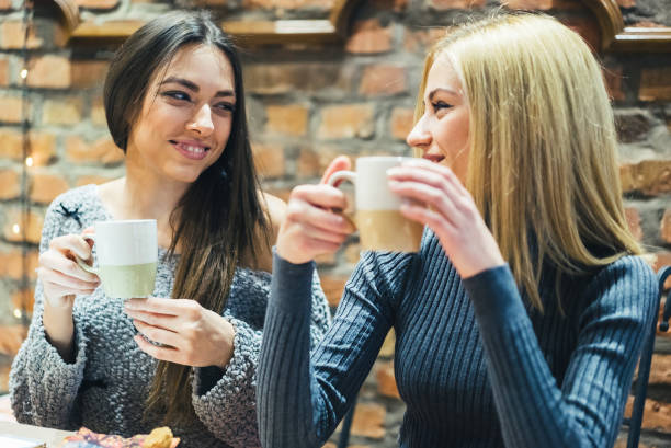 istock Two girls in cafe with hot drinks 1055628506