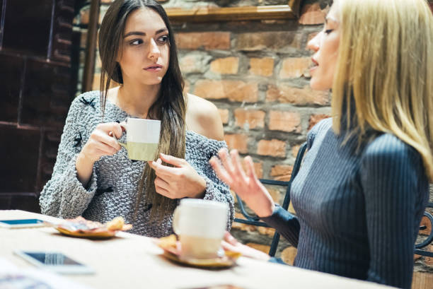 istock Two girls in cafe with hot drinks 1055628678