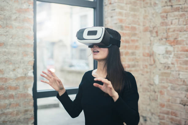 istock Young woman looks fascinated into Virtual Reality Headset 1055635312