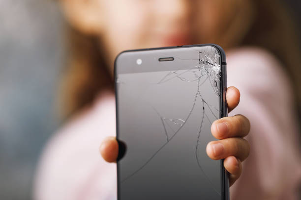 istock Broken phone in hands of small child, close-up 1055640460