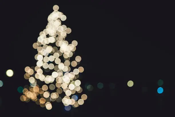 Photo of Abstract out of focus lights on a big Christmas tree outdoors at night. Ideal as a background or a design element.