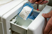 close up female hand pour the washing powder detergent into machine d