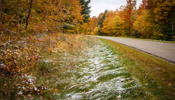 fall colors and first snow of season on rural michigan highway - country road winding road road michigan imagens e fotografias de stock