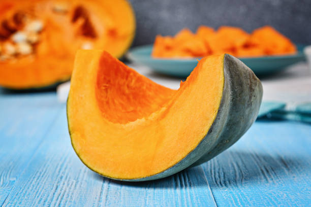 istock Sliced pumpkin into pieces for cooking pumpkin soup or mashed potatoes. Pumpkin on a blue wooden table. 1055646208