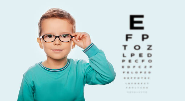 istock Little boy testing new eyeglasses, on the eye chart background 1055656468