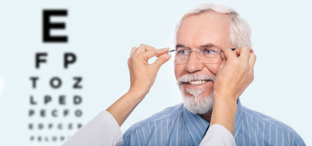 Optometrist is putting new glasses on senior man face Happy senior man trying out new reading glasses , on background eye chart. Mature man with new glases after eye exam eye test equipment stock pictures, royalty-free photos & images