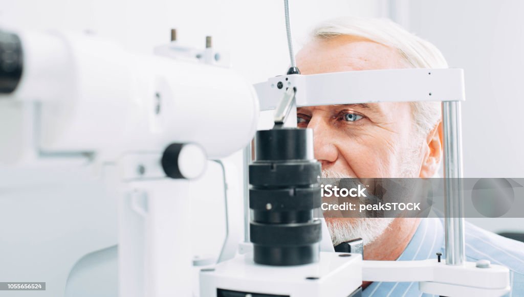 Senior man getting eye exam at clinic, close-up Senior patient checking vision with special eye equipment Eye Exam Stock Photo