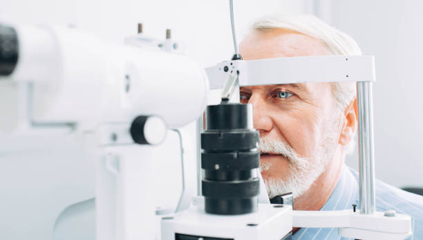 Senior man getting eye exam at clinic, close-up Senior patient checking vision with special eye equipment optometry stock pictures, royalty-free photos & images